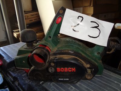 une machine verte, sur laquelle est accrochée une pancarte, posée à l'arrière d'un camion