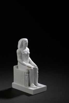 une image représentant une statue d'une femme assise sur un bloc de pierre