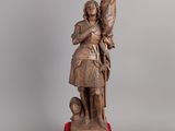 une vieille statue en bronze représentant un homme tenant une épée, posée sur un socle rouge