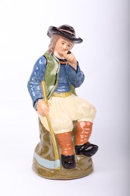 a figurine of a man sitting on a rock talking on a phone