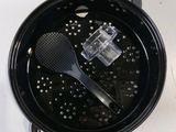 a black bowl with a black strainer and a black spoon