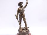 statue en bronze représentant un homme armé, posée sur un socle en bois