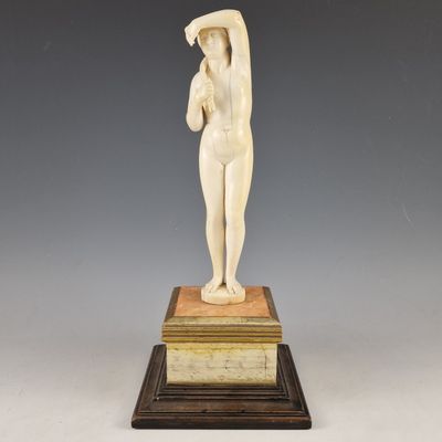 une statue blanche représentant une femme tenant une balle, posée sur un socle en marbre