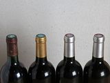 four bottles of wine are lined up on a wooden table