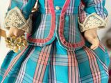 a doll that is wearing a dress and holding a flower