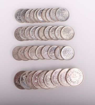 Plusieurs pièces d'argent sont alignées sur une surface blanche