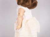 doll with brown hair and white dress standing on a gray surface