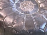 a black leather pouffe sitting on top of a table
