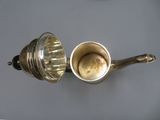 a silver teapot and a silver cup on a table