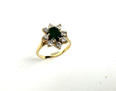 a close up of a ring with a green stone surrounded by diamonds