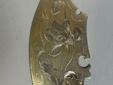 a silver spoon with a flower on it on a white surface