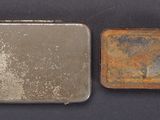 two small metal tins sitting next to each other on a table