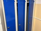 blue lockers in a bathroom with a toilet and a trash can