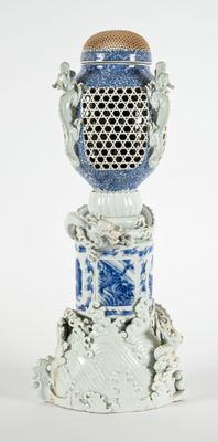 un vase bleu et blanc orné d'un couvercle doré, posé sur un socle