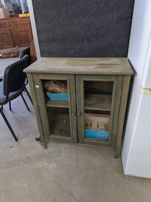 une petite armoire avec une porte vitrée et une chaise placée devant