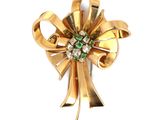 une image représentant une broche en or ornée de pierres vertes et blanches