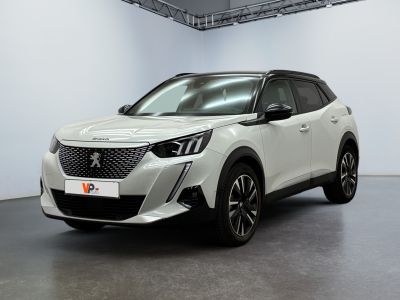 La voiture blanche est garée dans une grande pièce aux murs blancs.