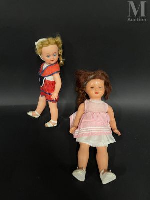 Deux petites poupées sont debout l'une à côté de l'autre sur une surface noire.