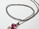collier avec un cristal rose et une chaîne en argent sur fond blanc