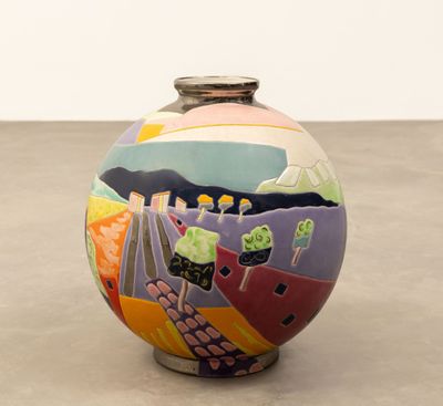 un vase coloré posé par terre, avec un mur blanc en arrière-plan