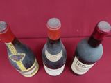 three bottles of wine are lined up on a red surface