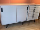 une armoire blanche avec des tiroirs, surmontée d'autres tiroirs, dans une pièce