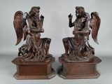 une paire de statues d'anges en bronze assis sur des socles, sur fond blanc