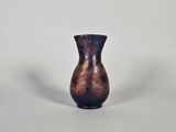 un petit vase posé sur une surface blanche