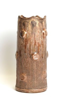 a brown vase with holes in it on a white surface