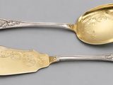 pair of silver spoons with engraved designs on them on a gray surface