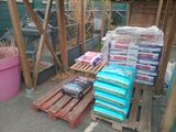 many bags of food sitting on pallets in the yard