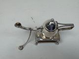 a silver object with a chain around it on a white surface
