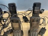 several cell phones are sitting on a wooden table with a charger