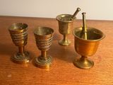 quatre tasses en laiton et un mortier posés sur une table en bois