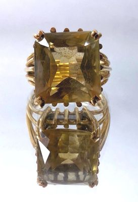 a close up of a gold ring with a large green stone