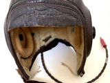un casque en cuir muni d'une visière en cuir, posé sur une surface blanche