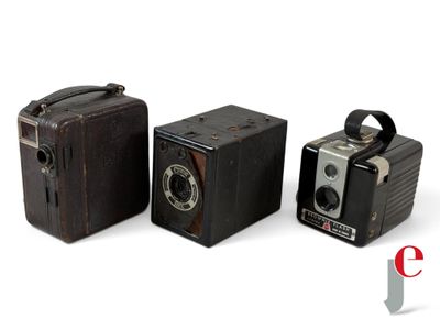 three old cameras sitting next to each other on a white surface