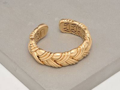 une image d'un bracelet en or sur une surface blanche
