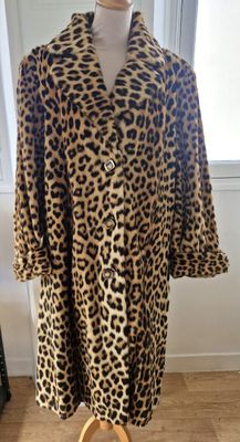 un manteau à imprimé léopard posé sur un mannequin devant une vitrine
