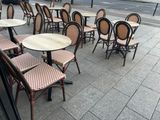 many tables and chairs on the sidewalk outside of a restaurant