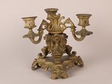 an antique brass candelab with three candles on a stand
