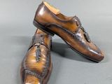 pair of men ' s brown leather shoes on a gray surface