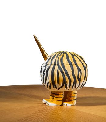 une figurine de tigre posée sur une table, sur fond blanc