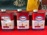 trois canettes d'esso à côté d'une banane sur une table