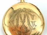 a gold pocket watch with a monogram on it