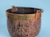 an old copper pot with a handle on a blue background