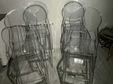 four clear chairs sitting next to each other on a wooden floor