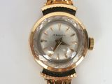 a gold wrist watch with a white face on a white surface