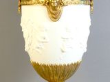 un vase blanc et doré posé sur un socle, sur fond gris