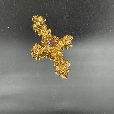 une croix en or sertie d'une pierre rose